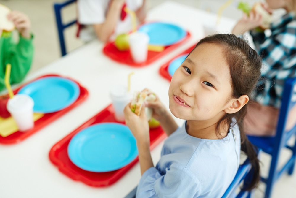 niña come feliz en cafeteria colegio