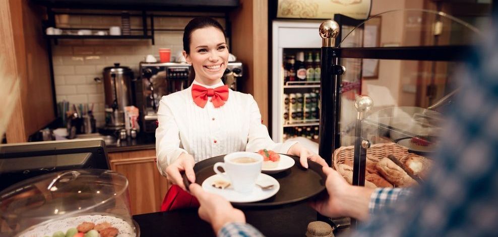 camarera sonriente con pajarita entrega bandeja a cliente